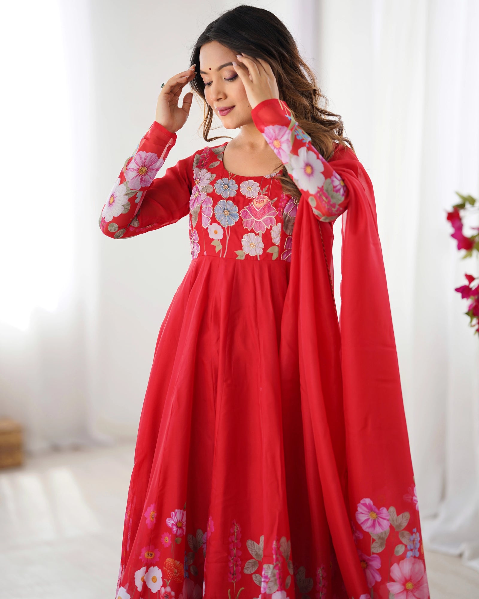 Woman wearing a red traditional outfit with floral embroidery on a white background