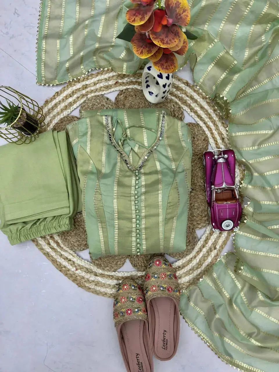Close-up flat lay of mirror work neckline and cuff detail on pastel green suit