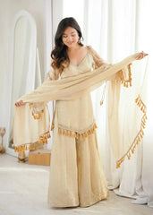 KU212 Beige Suit – Full-length shot with model holding dupatta wide while looking down, showing V-neck detail and bell sleeve tassel cuffs