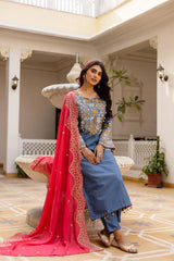 KU216 Grayish Blue Cotton Denim Embroidered Suit – Seated pose with coral-pink Zari Border dupatta, showing yoke embroidery detail