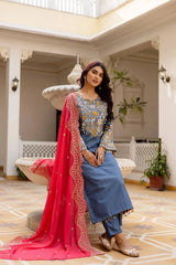 KU216 Grayish Blue Cotton Denim Embroidered Suit – Seated pose with coral-pink Zari Border dupatta, showing yoke embroidery detail