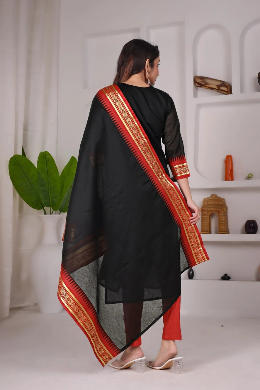 Woman wearing a black saree with red border in a minimalistic setting