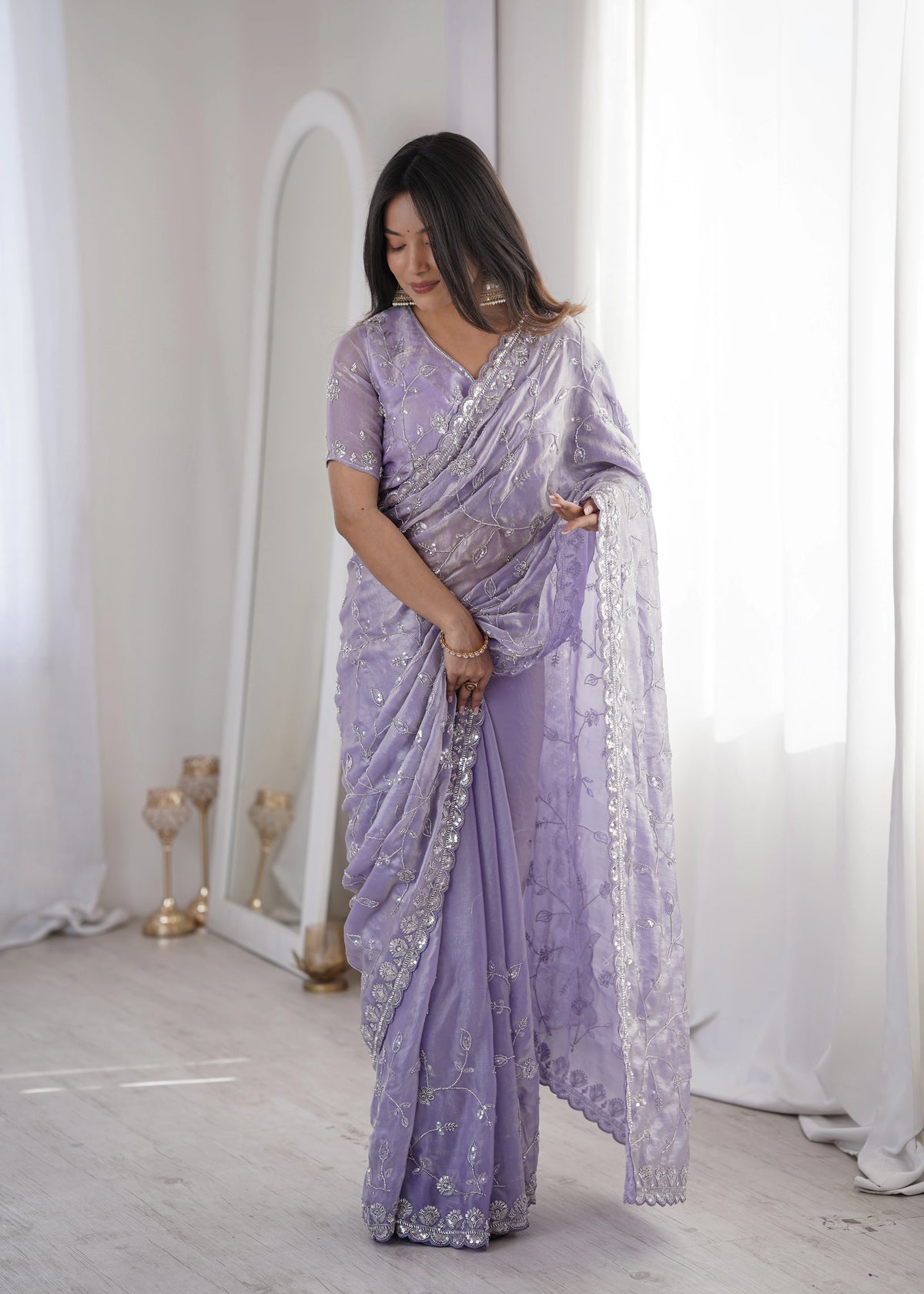 Woman wearing a lavender saree with white patterns in a minimalistic setting.