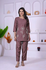 Woman wearing a brown outfit with floral patterns in a white room.