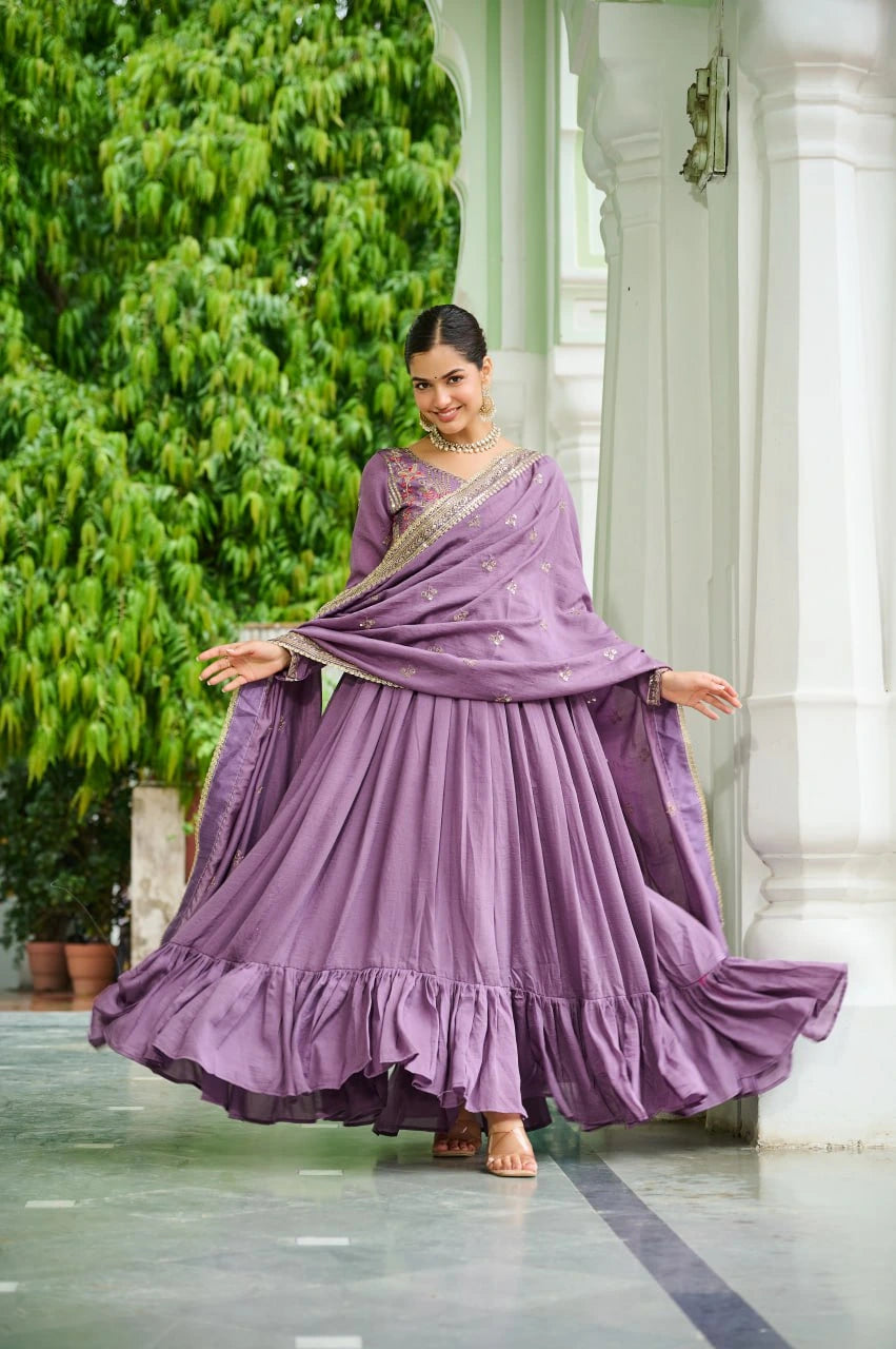 Woman in a purple traditional outfit standing in a garden setting