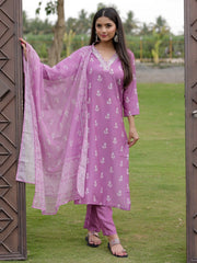 Woman in a purple traditional outfit with a pink dupatta standing outdoors.