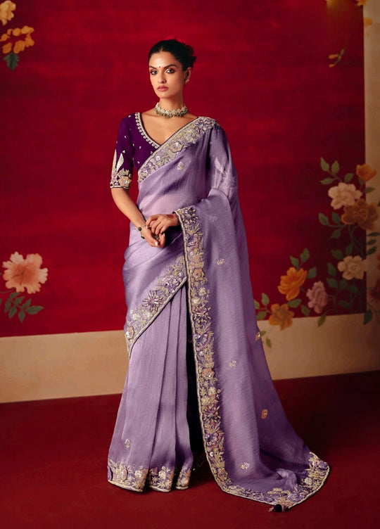 Woman wearing a purple saree with floral decorations in the background