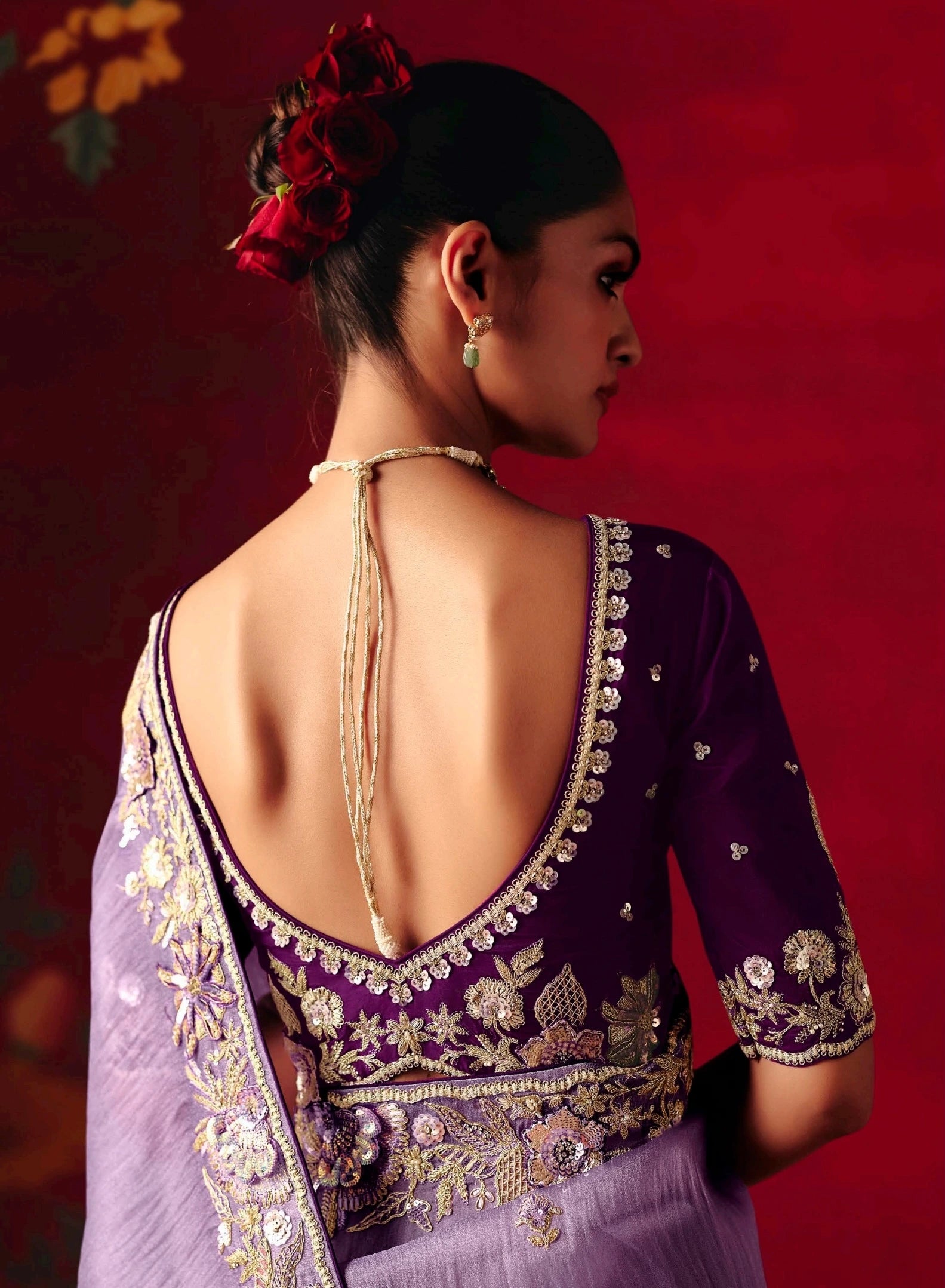 Woman wearing a traditional embroidered outfit with a red background