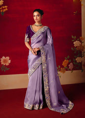 Woman wearing a purple saree with floral decorations in the background