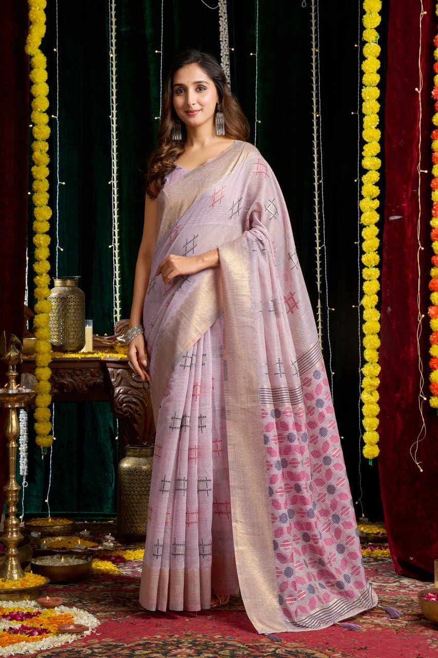 Woman in a light pink saree with a floral pattern against a decorated backdrop