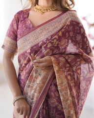 Woman wearing a purple saree with floral patterns and gold jewelry.