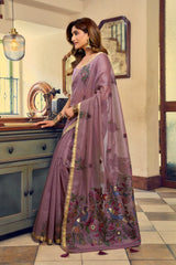 Woman in a purple saree with floral patterns standing in a kitchen.