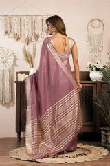 Woman in a mauve saree with a white blouse in a decorated room.