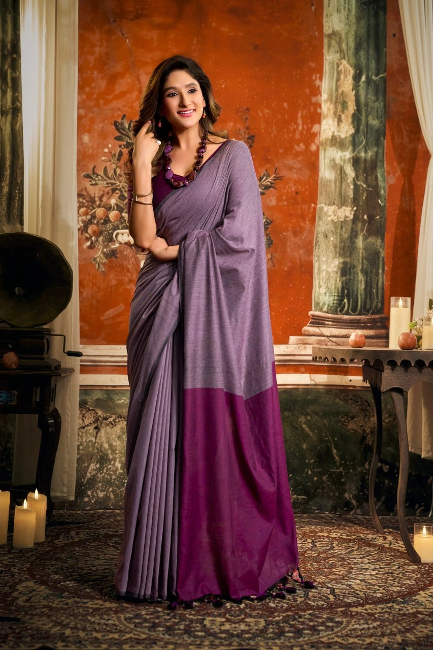 Woman in a purple saree standing in an elegant room with candles and decorative elements.