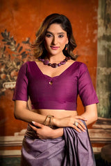 Woman wearing a purple blouse and saree with a textured wall background