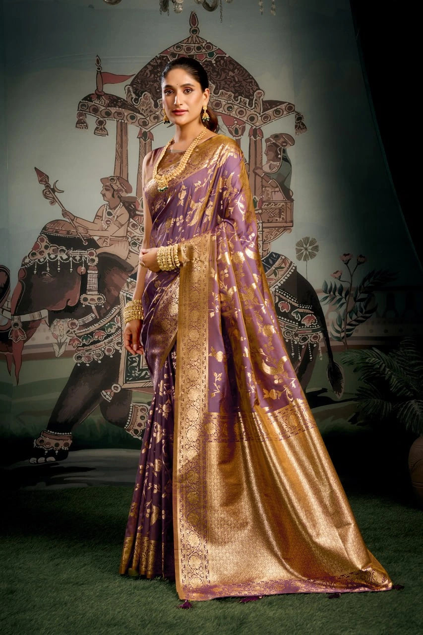 Woman in a traditional purple and gold saree against an ornate wall.