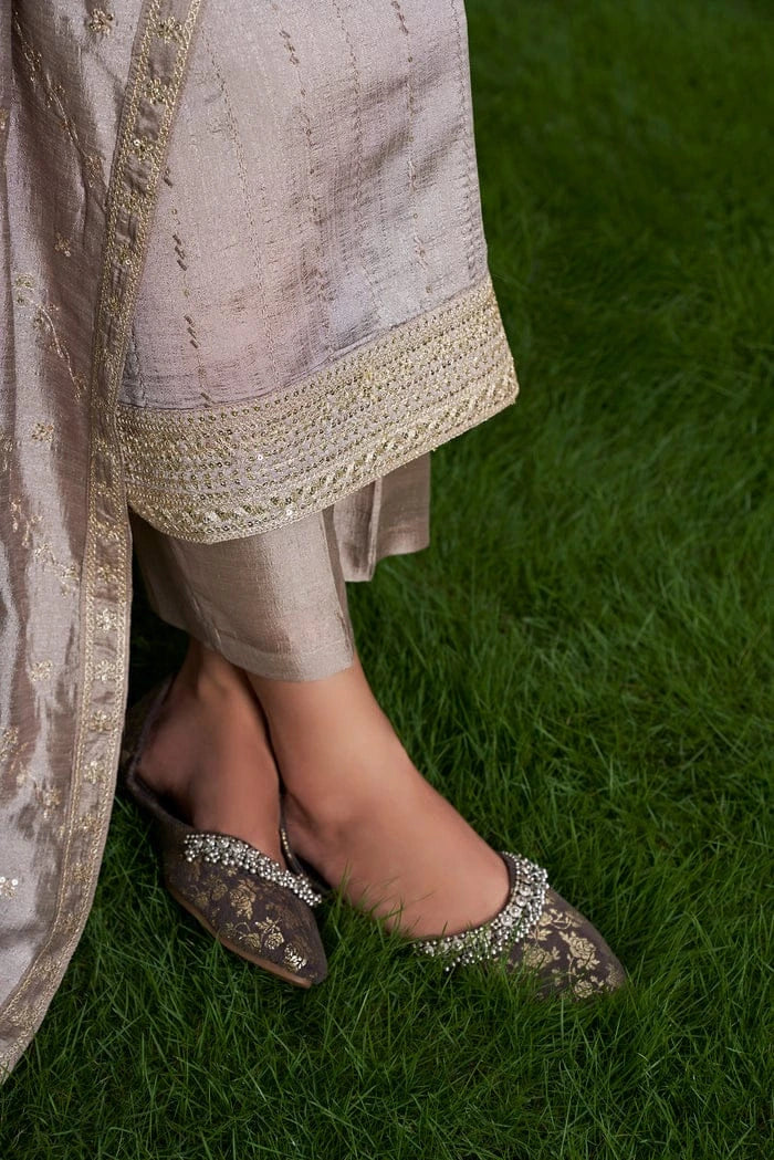 Person wearing a traditional outfit with embellished shoes on grass