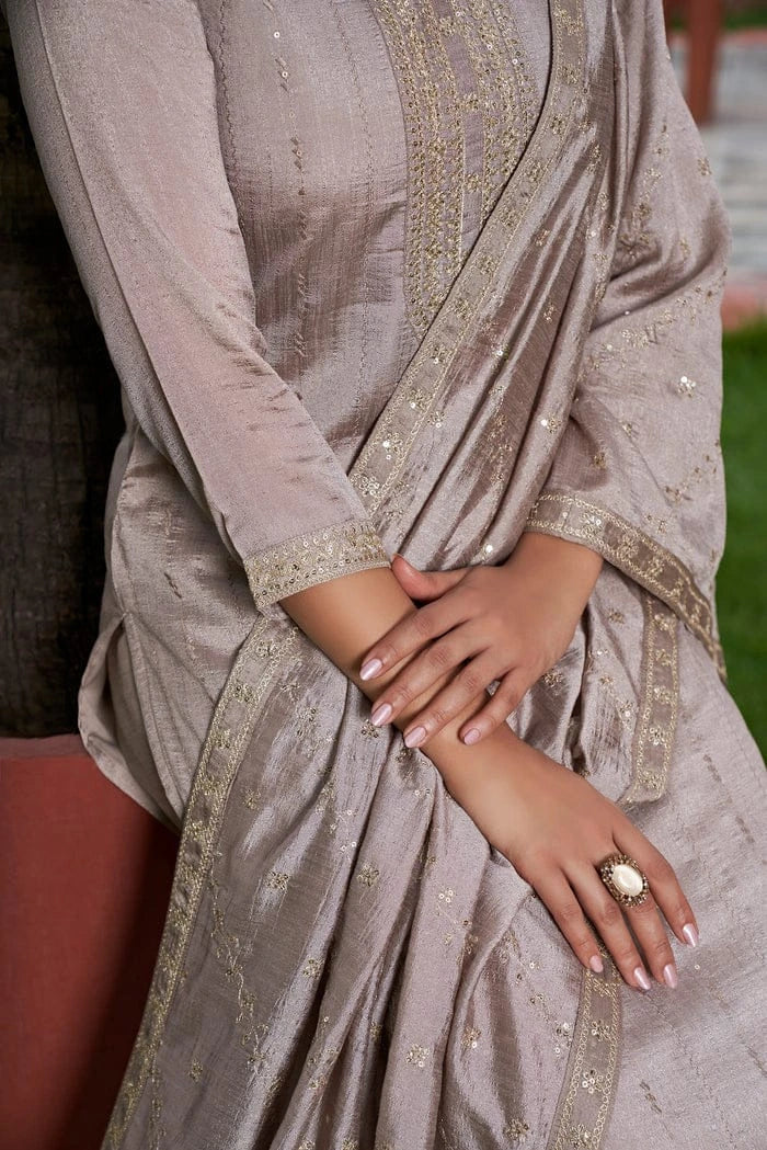 Close-up of a person wearing a light brown saree with intricate patterns.