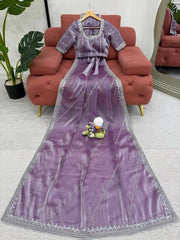 Purple dress with silver trim on a hanger in a room with a red sofa and plant.