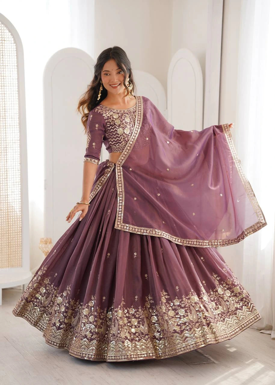 Woman wearing a mauve saree with gold embroidery in a bright room.
