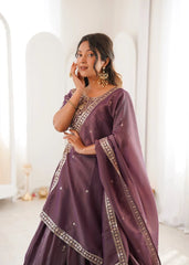 Woman wearing a purple traditional outfit with gold embroidery in a bright room.