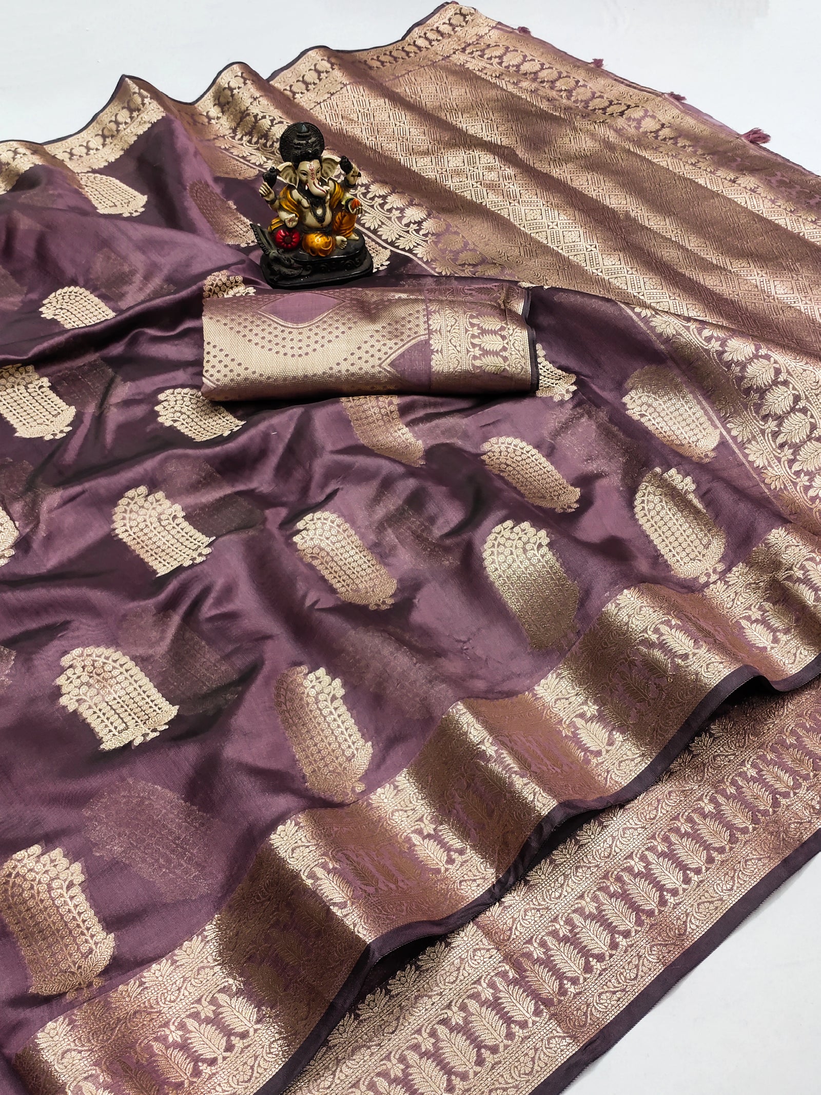 Purple and beige saree with a decorative item on a white background