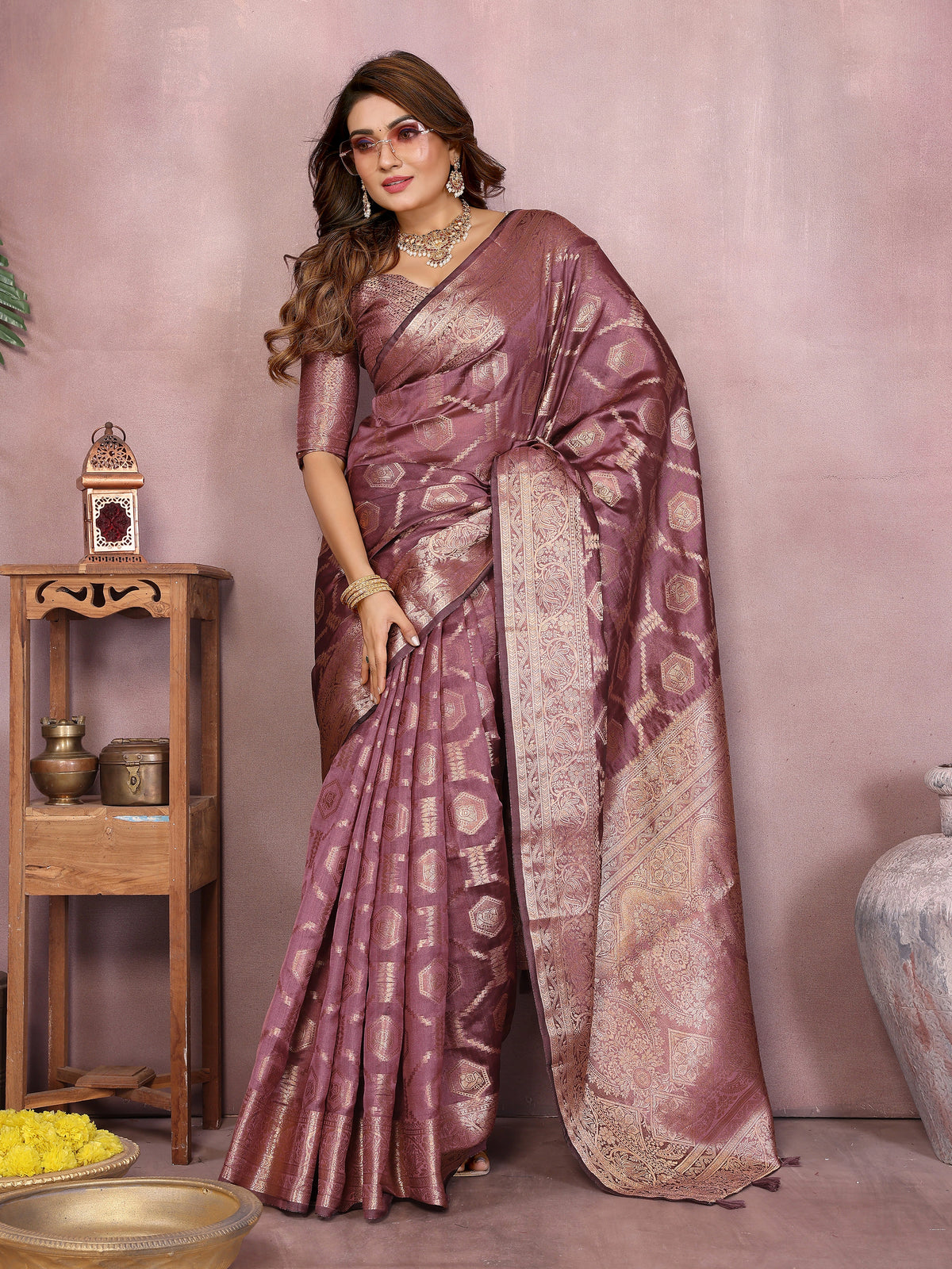 Woman wearing a traditional saree with intricate patterns in a decorative setting.