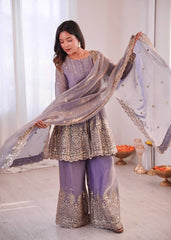 Woman in traditional outfit with embroidered dupatta in a well-lit room.