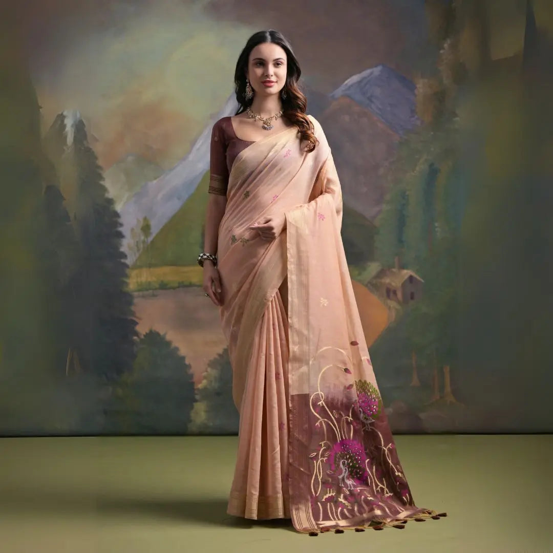 A woman models a soft Light Peach Muga Silk Saree with subtle Resham weaving. The pallu dramatically transitions to a dark brown/maroon color, featuring intricate pink and purple floral Resham threadwork. She wears a dark brown blouse and a gold Kundan necklace.
