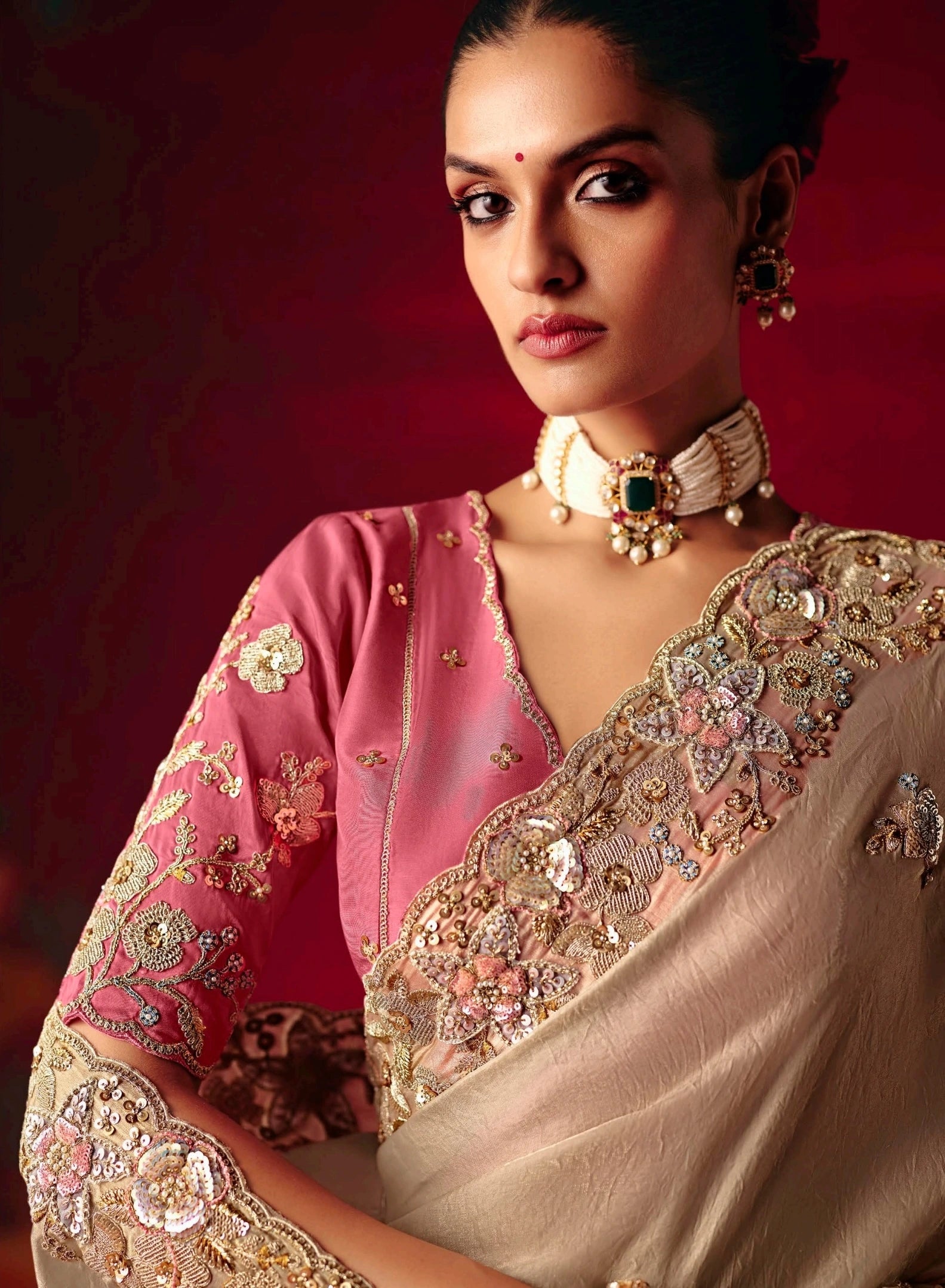 Woman wearing a traditional embroidered saree with a red background