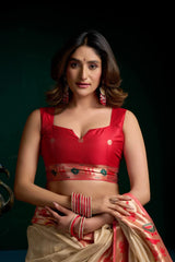 Woman wearing a red blouse and beige saree with a dark background