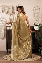 Woman in a gold saree standing in a room with decorative elements.