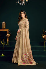 Woman wearing a beige saree with floral patterns in a dark setting