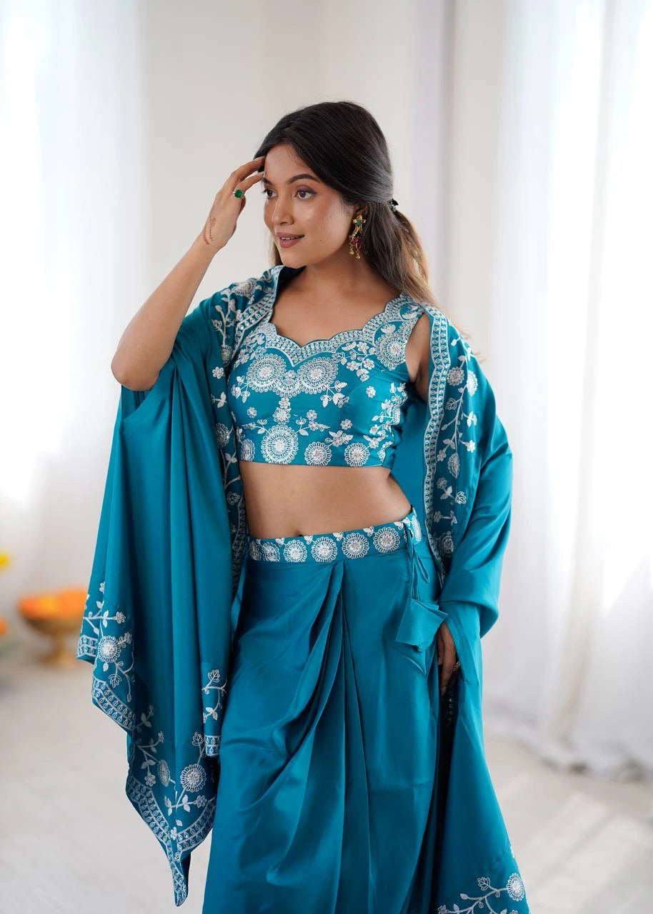 Woman wearing a teal traditional outfit with white embroidery indoors.