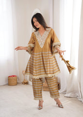 Woman wearing a traditional outfit with intricate patterns in a bright room.