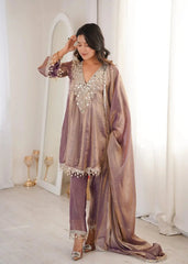 Woman in a traditional outfit with intricate designs in a softly lit room.
