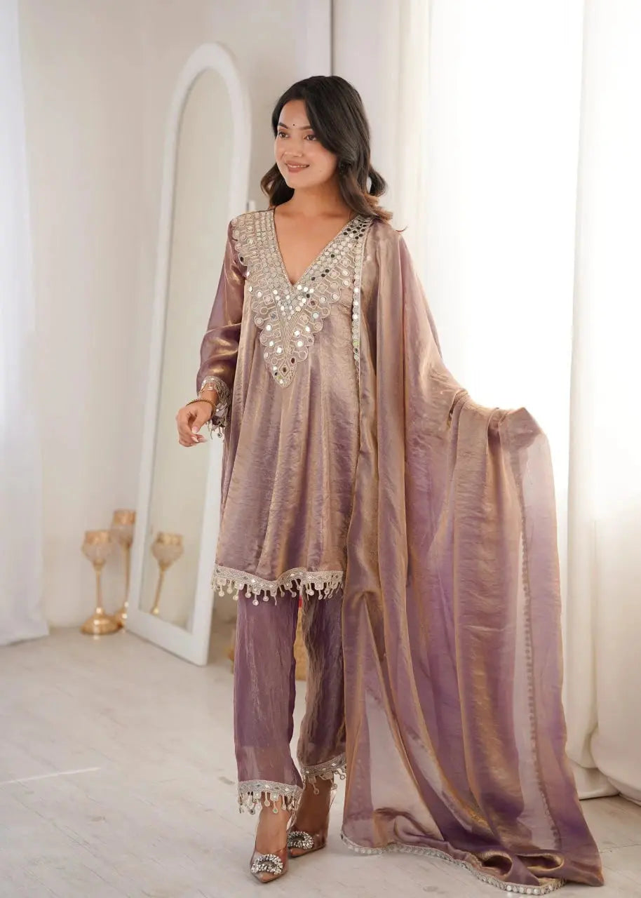 Woman wearing a traditional outfit with embellishments in a softly lit room.