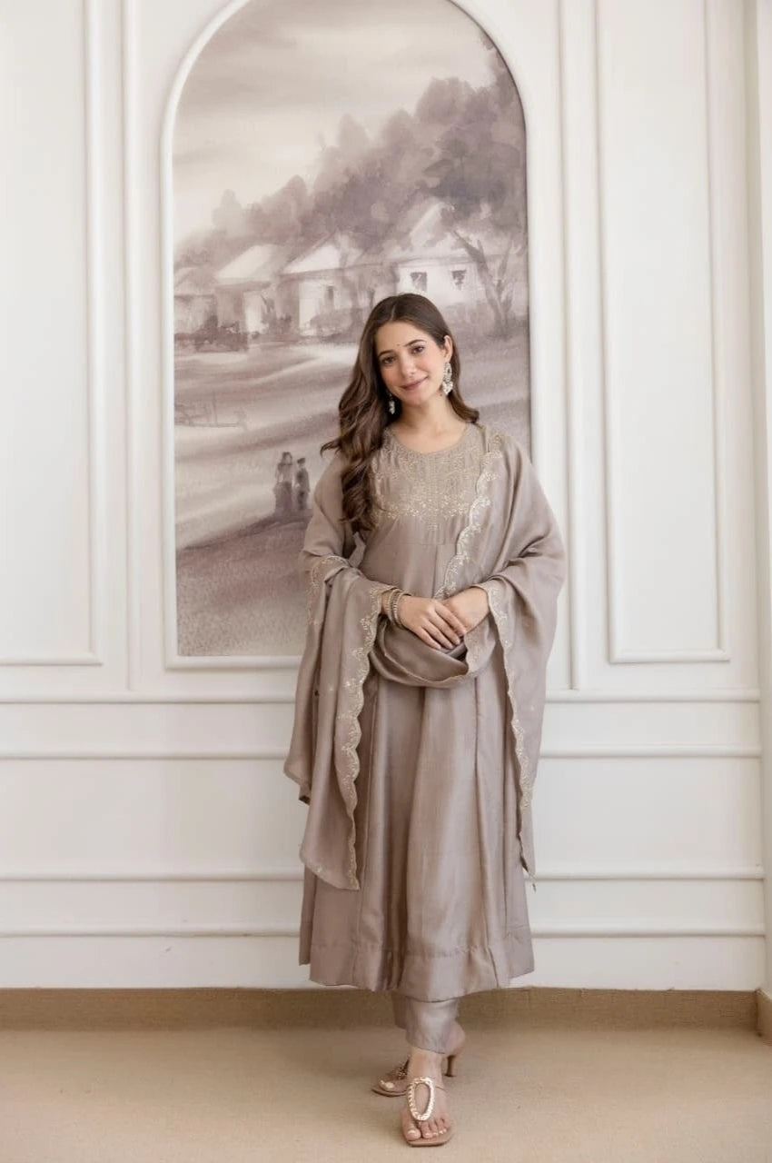 Woman in a gray traditional outfit standing in a room with decorative wall art.