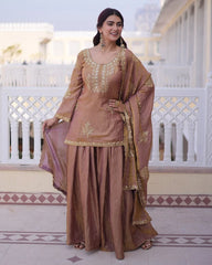 Woman in a traditional outfit with gold embroidery standing on a balcony.