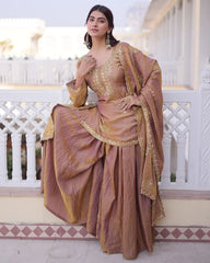 Woman in a traditional outfit with gold and brown colors standing in front of a white architectural background.