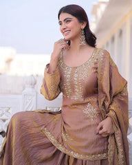Woman in a traditional outfit with gold embroidery sitting on a white bench.