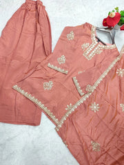 Peach-colored traditional outfit with intricate gold embroidery on a light gray background