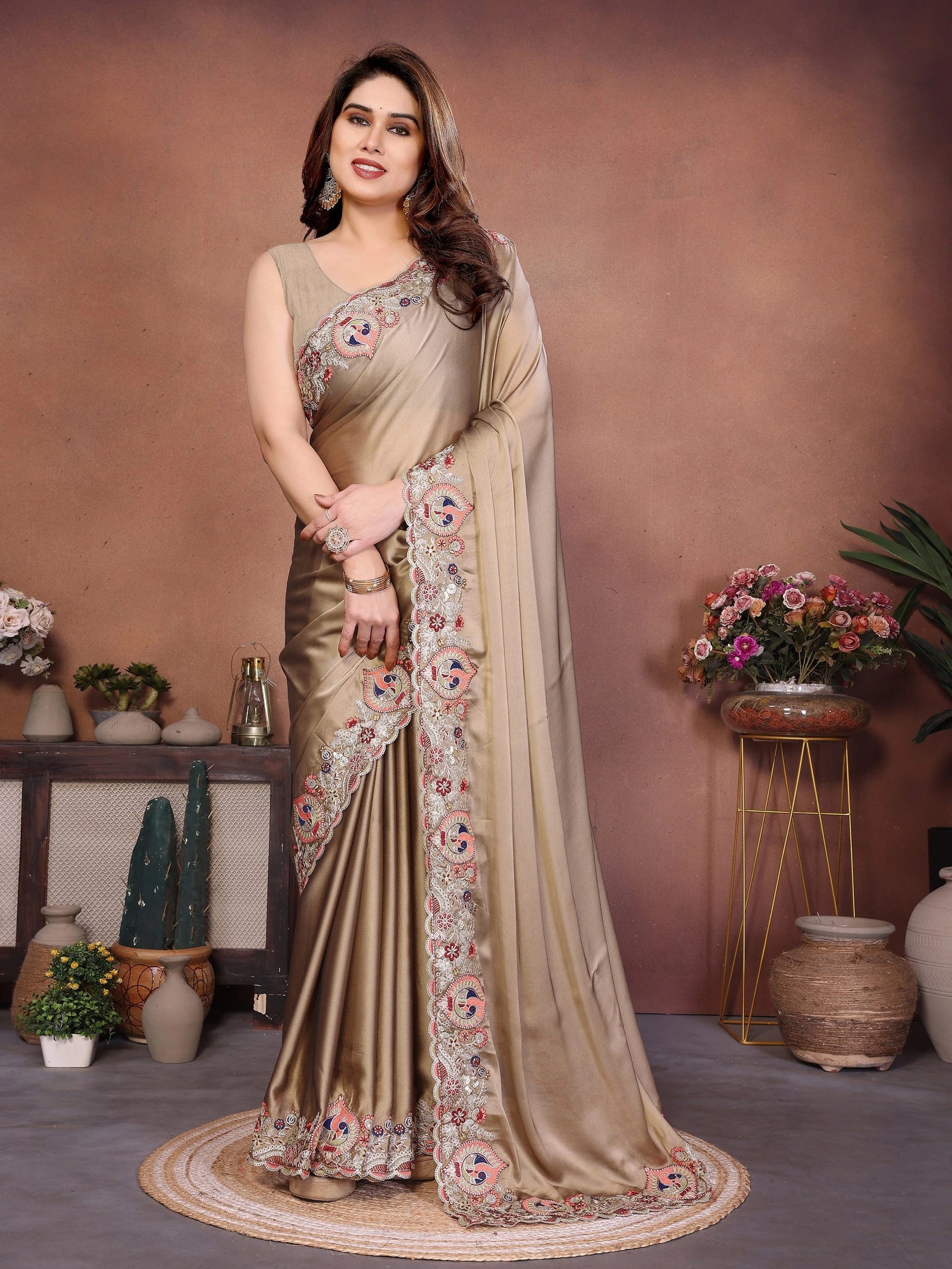 Woman wearing a beige saree with floral patterns in a decorated room.