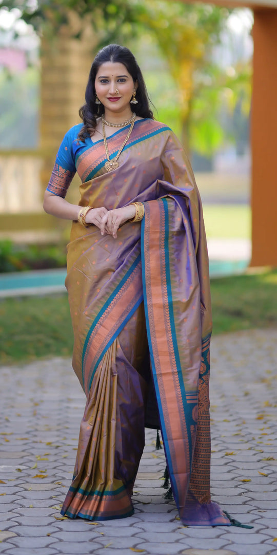 Woman in a traditional saree standing outdoors on a paved path with greenery in the background