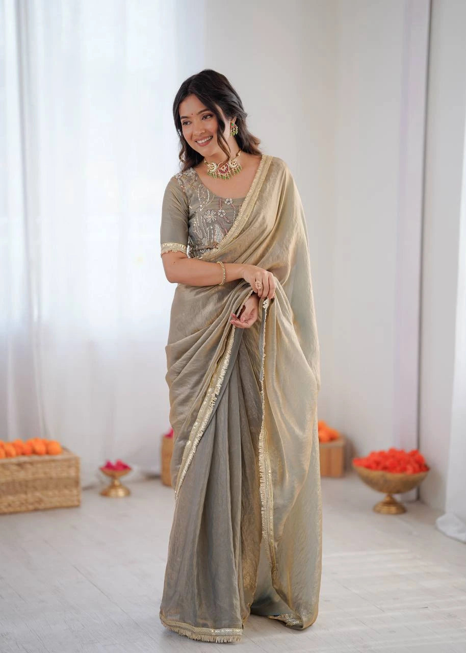 Woman wearing a traditional saree with a neutral color palette in a minimalistic setting.