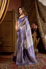 Woman in a purple saree standing in an ornate room with decorative curtains and decor.