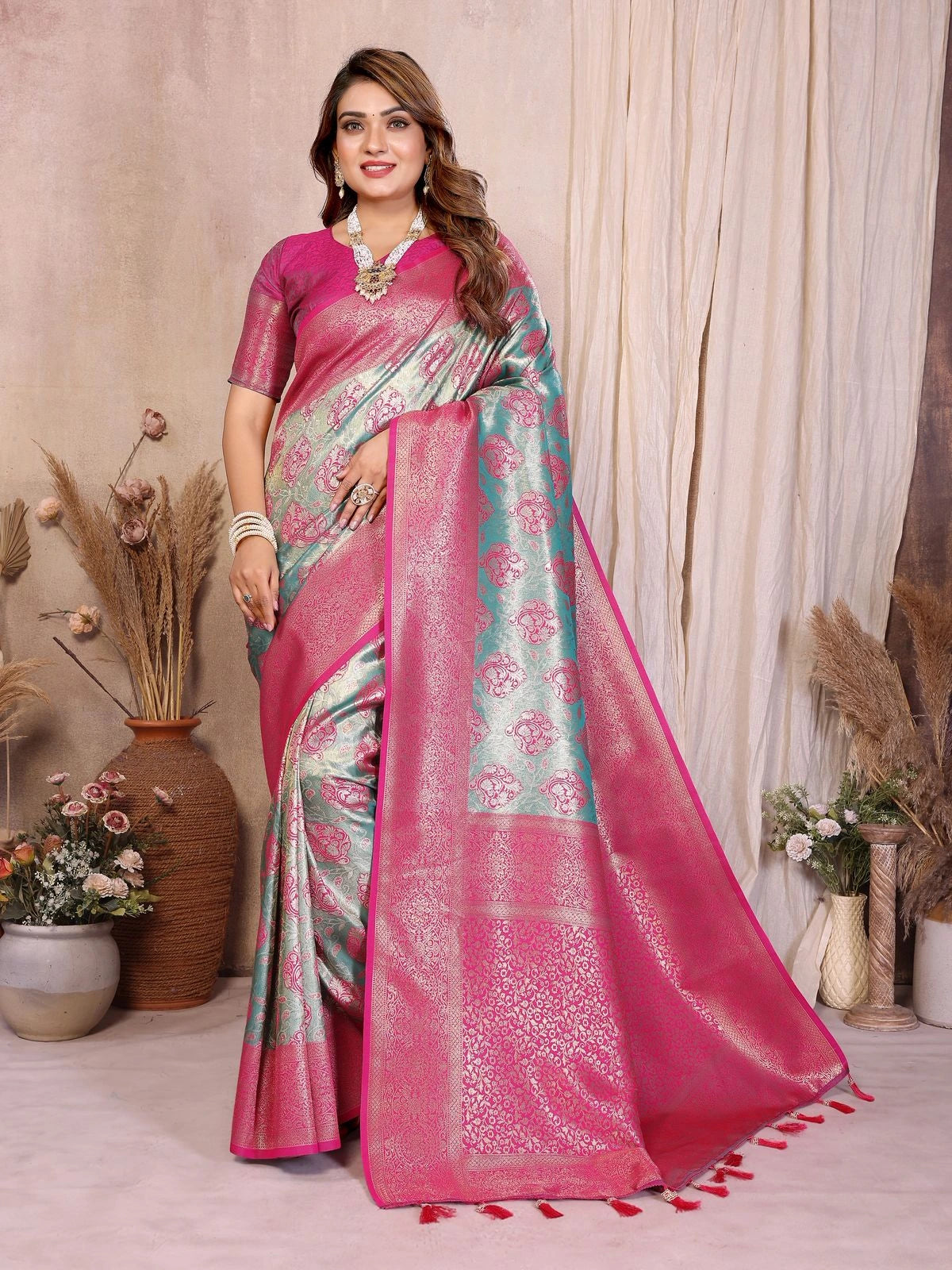 Woman wearing a pink saree with a floral pattern in a decorated room.