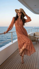 Woman in a patterned dress and sun hat standing on a yacht deck with ocean view.