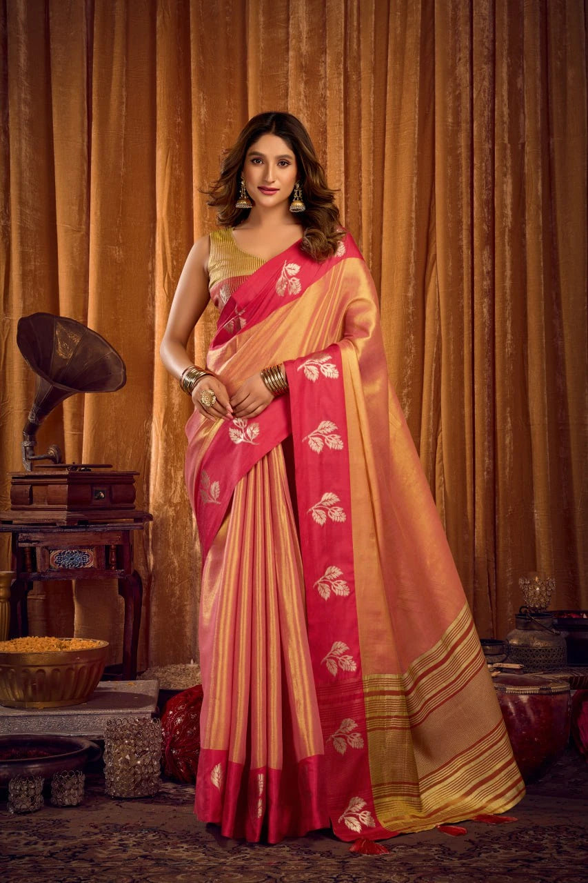 Woman in a pink and gold saree standing in front of a vintage gramophone and curtains.