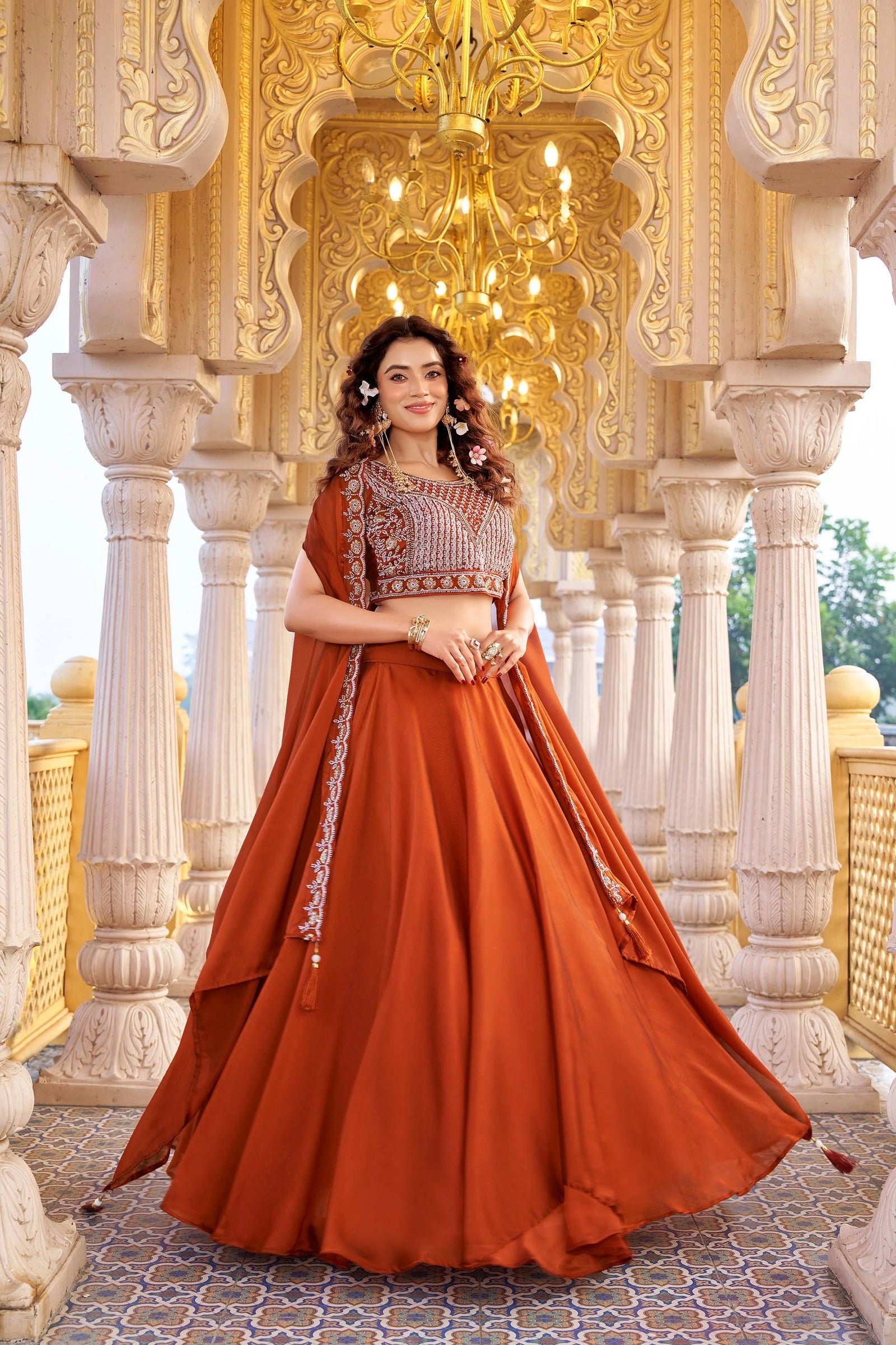 Woman in a traditional orange outfit standing in an ornate architectural setting.